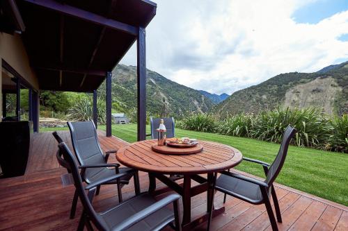 a wooden table and chairs on a deck with mountains at Glencree Luxury Chalets in Kaikoura