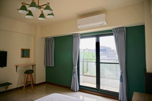 a bedroom with a green wall and a window at Ｏn the road in Donggang