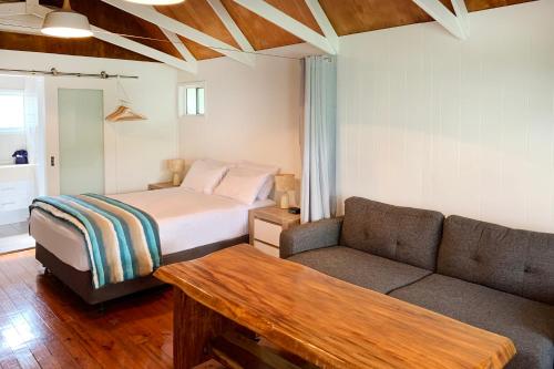 a bedroom with a bed and a couch and a table at Airlie Beach Magnums - Adults Only in Airlie Beach