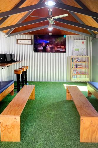 a room with two wooden benches and a flat screen tv at Airlie Beach Magnums - Adults Only in Airlie Beach
