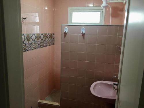 a pink bathroom with a sink and a window at Apartamento PRAIA do TOMBO - Guarujá in Guarujá