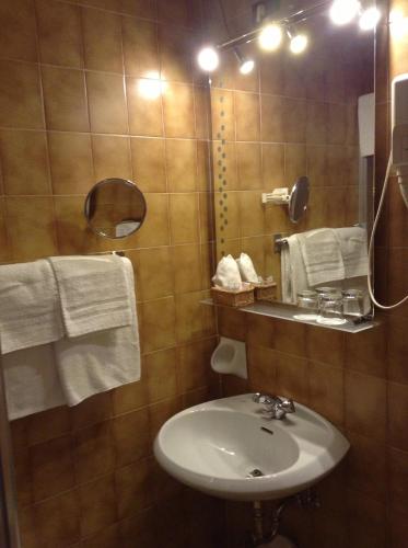 a bathroom with a sink and a mirror and towels at Hotel Ai Pini in Vigo di Fassa