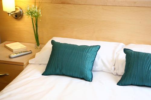 1 cama con 2 almohadas y un jarrón de flores sobre una mesa en David Russell Apartments - Campus Accommodation en St Andrews