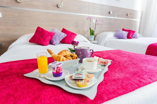 a tray of breakfast food on a bed with two beds at Hôtel de l'Europe Grenoble hyper-centre in Grenoble