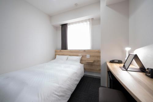 a bedroom with a bed and a desk and a window at Washington R&B Hotel Nagoya Shinkansenguchi in Nagoya