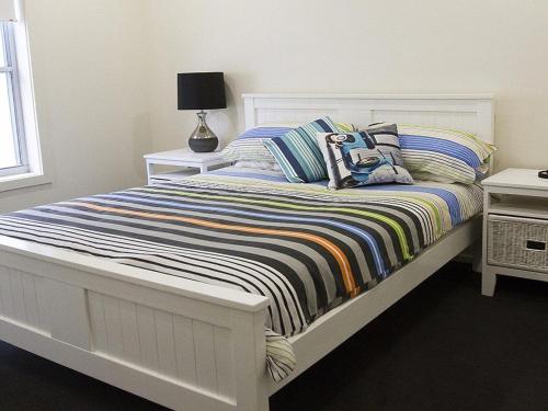 1 dormitorio con 1 cama con manta a rayas en Jones Beach House, en Kiama Downs