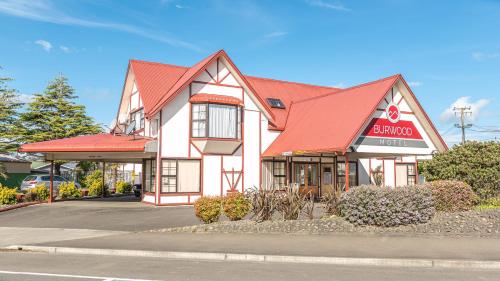 a building with a red roof in a parking lot at Burwood Motel in Whanganui