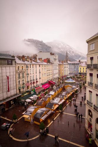 a city with a market with a mountain in the background at Hôtel de l'Europe Grenoble hyper-centre in Grenoble