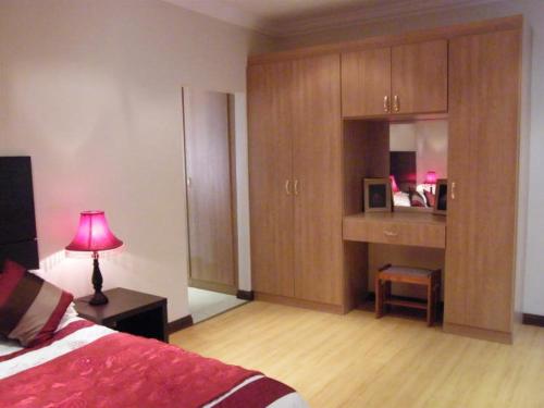 a bedroom with a bed and a desk with a pink lamp at Littlefield Luxury Suite in Johannesburg
