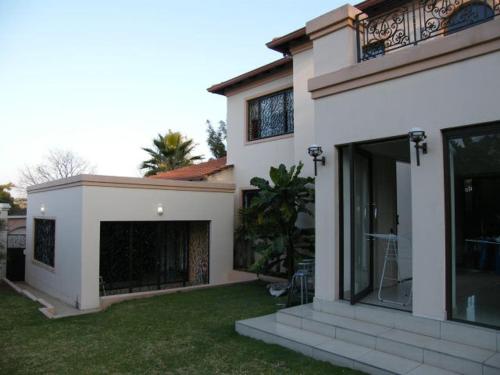 a white house with large windows and a yard at Littlefield Luxury Suite in Johannesburg