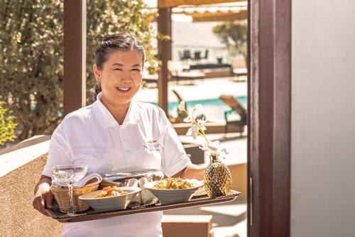 a woman is holding a tray of food at Sahab Resort and Spa, Jabal Al Akhdar in Al ‘Aqar