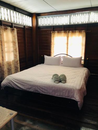 a bed with two green towels on top of it at Banthai Guesthouse in Phetchaburi