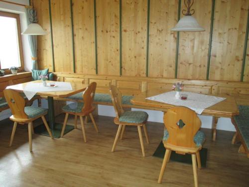 two tables and chairs in a room with wooden walls at Bamerhof in Mittersill
