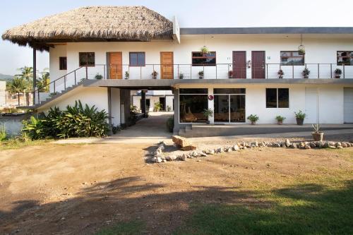 a large white building with a thatched roof at Hotel Samanu in Sayulita