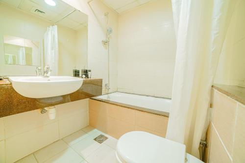 a bathroom with a sink and a toilet and a tub at OYO 585 Home 120, B block, Diamond Views 1 in Dubai