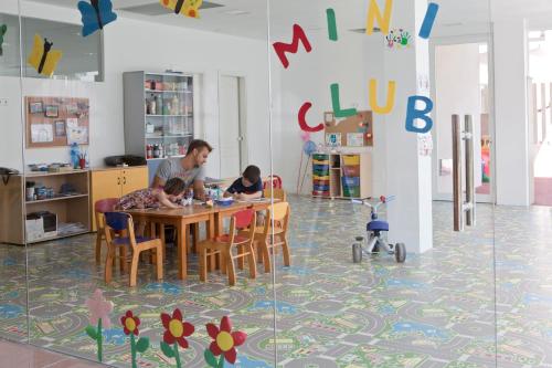 a man and two children sitting at a table in a classroom at Aparthotel Isla de Cabrera in Colonia Sant Jordi