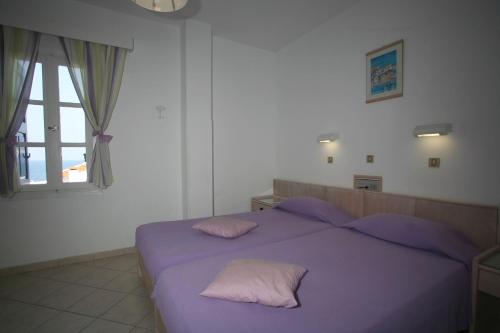 a bedroom with a purple bed with two pillows at Lemos Hotel in Kokkari