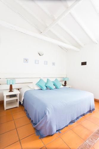a bedroom with a large bed with blue pillows at Hotel y Spa Getsemani in Villa de Leyva