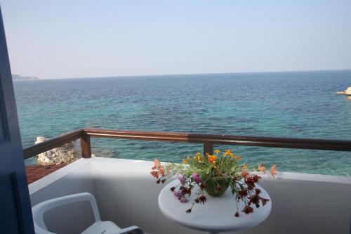 a table with flowers on a balcony overlooking the ocean at Lemos Hotel in Kokkari