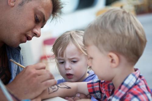 a man drawing a tattoo on a young child at Aparthotel Isla de Cabrera in Colonia Sant Jordi