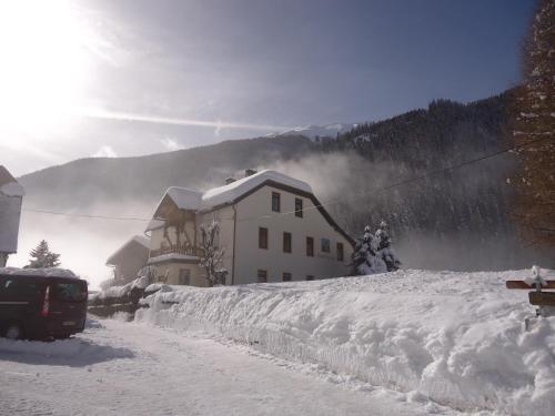 ein Haus auf einem schneebedeckten Hügel mit einem Gebäude in der Unterkunft Haus Obernig in Mallnitz