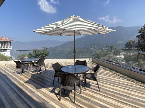 a patio with two tables and chairs and an umbrella at Zone Connect by The Park Mussoorie in Mussoorie