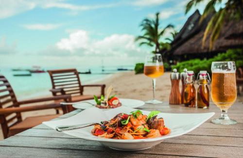 a table topped with plates of food and drinks at Paradis Beachcomber Golf Resort & Spa in Le Morne