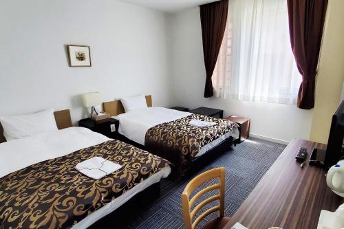 una habitación de hotel con 2 camas y una silla en Tachikawa Regent Hotel en Tachikawa