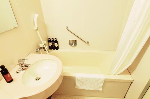 
a white bath tub sitting next to a white sink at Tachikawa Regent Hotel in Tachikawa
