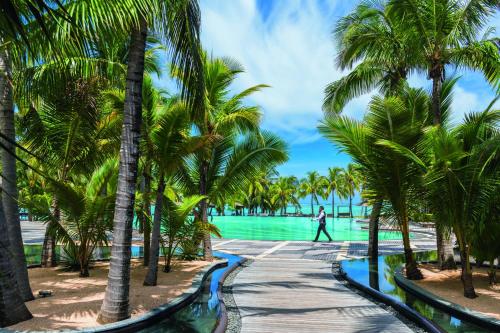 a beach filled with palm trees and palm trees at Dinarobin Beachcomber Golf Resort & Spa in Le Morne