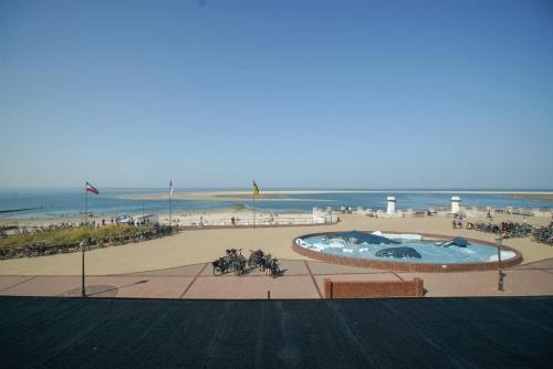 a view of a beach with a swimming pool and the ocean at Strandhotel Ostfriesenhof in Borkum