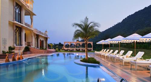 a swimming pool with white chairs and a building at Rajasthali Resort & Spa in Jaipur