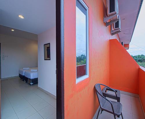a room with an orange wall with a chair and a bed at Dna Fun Zone Pekanbaru in Pekanbaru