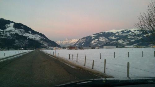 a snowy road with a fence and snow covered mountains at Alpenappartement Claudia in Piesendorf