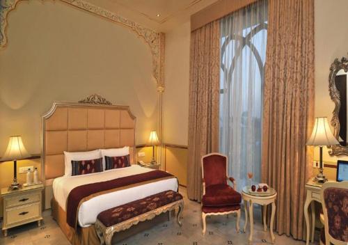 a bedroom with a bed and a chair and a window at Rajasthali Resort & Spa in Jaipur