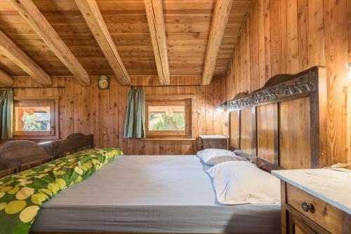 a large bed in a room with wooden walls at Baita Pizabornè in Groppe de Fora