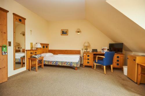 Schlafzimmer mit einem Bett, einem Schreibtisch und einem TV in der Unterkunft Flair-Hotel Zum Benediktiner in Schwarzach am Main