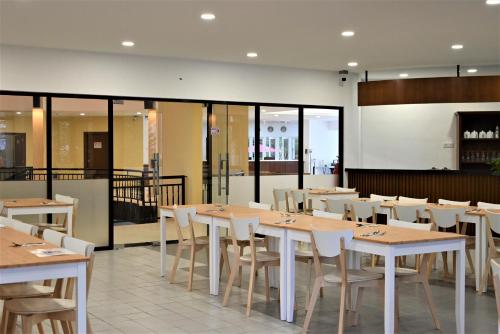 - une salle à manger avec des tables, des chaises et des fenêtres dans l'établissement The Pines at Fraser's Hill, Malaysia, à Bukit Fraser
