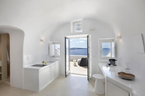a white bathroom with a view of the ocean at Apanema Cavehouses Santorini in Oia