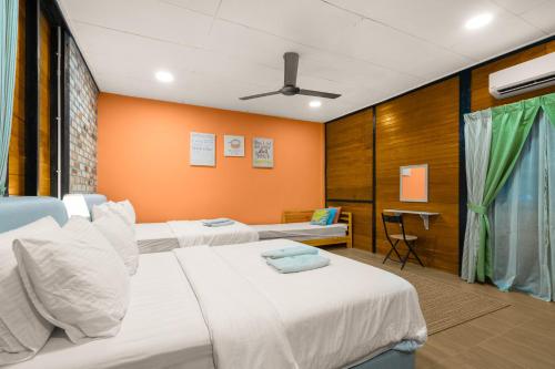 two beds in a room with orange walls at Villa Kiambang in Seremban