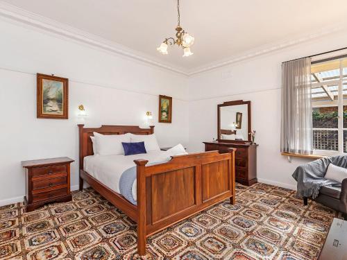 1 dormitorio con cama, espejo y sofá en Bloom on Sackville Opt1, en Port Fairy
