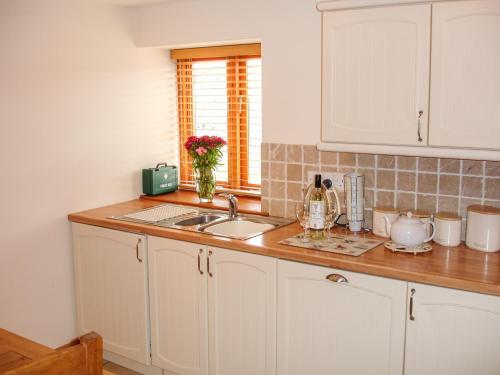a kitchen with white cabinets and a sink and a window at The Hagguard in Kilgetty