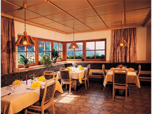 een restaurant met witte tafels, stoelen en ramen bij Gasthof Mittermühl in Funes