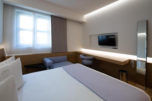 a room with a bed and a flat screen tv at Domotel Kastri in Athens