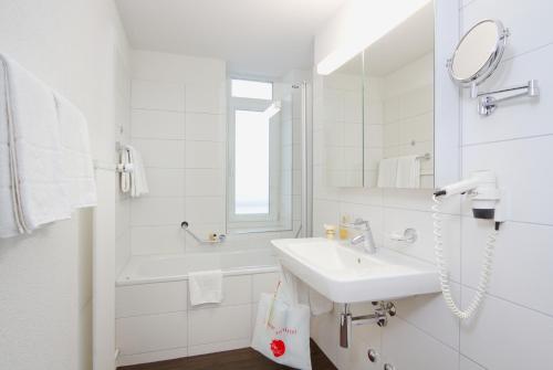een witte badkamer met een wastafel en een spiegel bij Central Apartments Davos in Davos