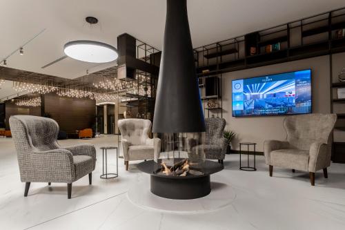 a living room with a fireplace and chairs and a tv at Hotel Bulgaria in Burgas City