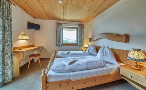 a bedroom with a bed and a desk and a window at Sportpension Enzian in Saalbach Hinterglemm