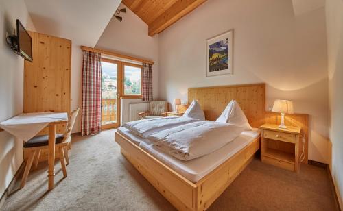 a bedroom with a bed and a table and a desk at Sportpension Enzian in Saalbach Hinterglemm