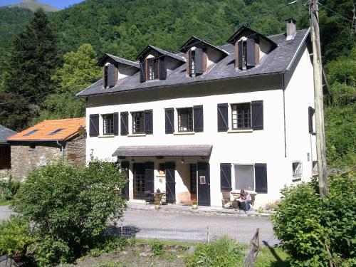 une grande maison blanche avec des fenêtres à volets noirs dans l'établissement Auberge Les Myrtilles, à Couflens