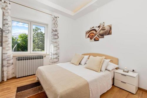a white bedroom with a bed and a window at Holiday house with swimming pool in Viskovo